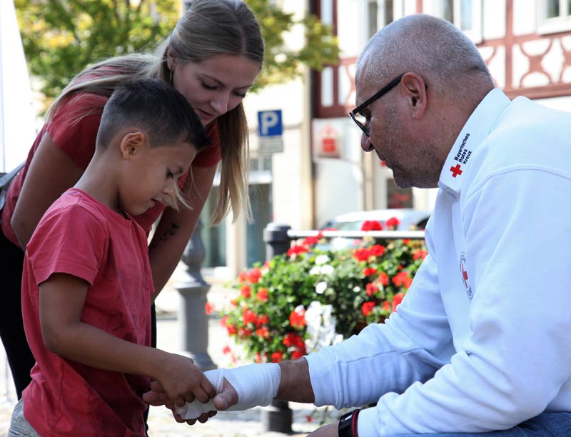 Erste Hilfe ist kinderleicht. Hier legt ein Junge bei Rettungsassistent Jürgen Krumpholz einen Verband an der Hand an – ein Kinderspiel. (Foto: Michael Will / BRK)