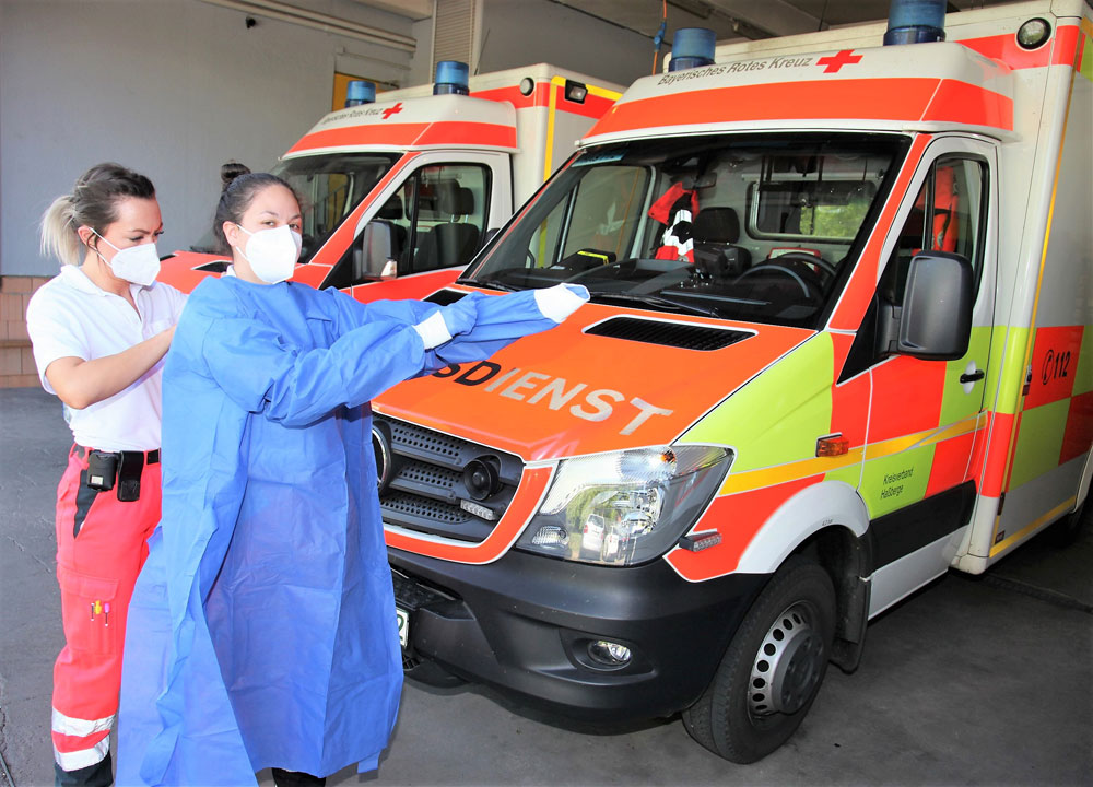 Um sich vor einer möglichen Ansteckung zu schützen, tragen die Rettungsdienstmitarbeiter bei der Behandlung bzw. dem Transport von Patienten mit potentieller Covid-19-Infektion Schutzkleidung. Dazu gehören neben einer FFP2-Maske, Schutzhandschuhe, ein Schutzkittel und eine Schutzbrille. Notfallsanitäterin Wiebke Göhringer (links) und Rettungssanitäterin Milena Perez Viera zeigen fürs Foto, wie das aussieht. (Foto: Michael Will)