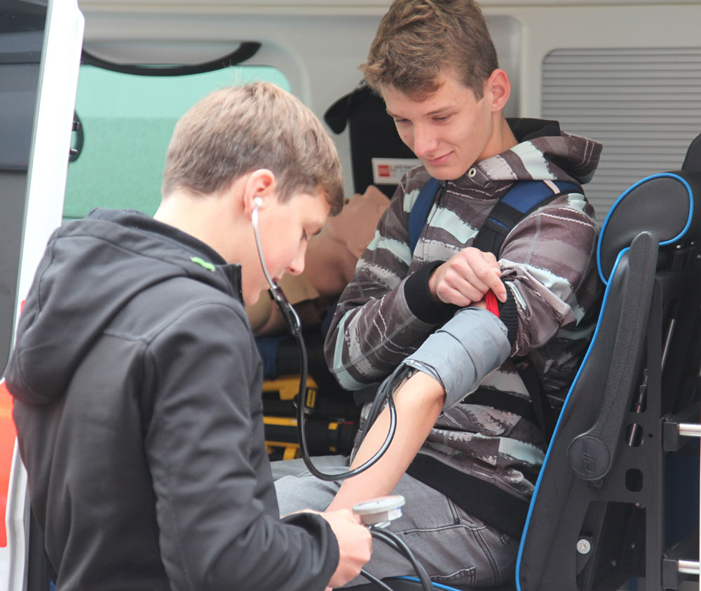Beim Blutdruckmessen üben die Schüler den Umgang mit Blutdruckmanschette und Stethoskop.   (Foto: Michael Will / BRK)