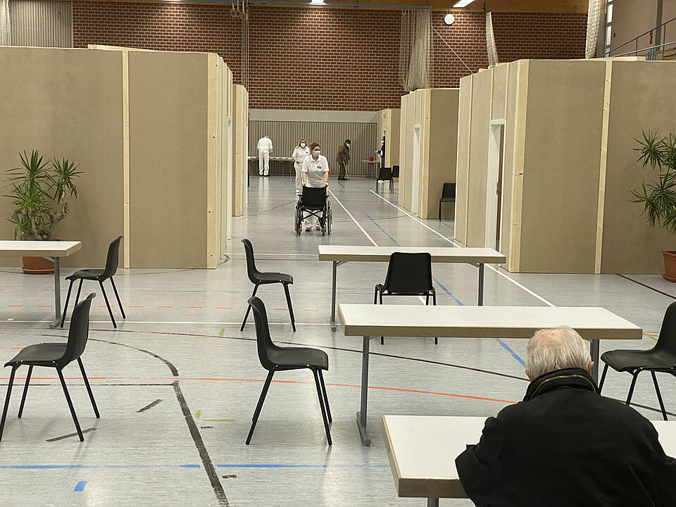 Ein Blick ins Halleninnere: Vorne der Wartebereich, in dem die Impflinge ihre Unterlagen ausfüllen, dahinter mehrere Boxen für Arztgespräche und die eigentliche Impfung. Für Senioren mit Gehschwierigkeiten hält das BRK auch Rollstühle vor. (Foto: Michael Will / BRK)