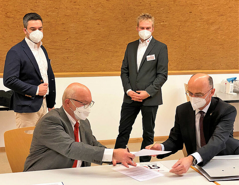 Landrat Wilhelm Schneider (rechts) und BRK-Kreisgeschäftsführer Dieter Greger (links) unterzeichneten am Dienstagmittag die Kooperationsvereinbarung zwischen Landkreis und Bayerischem Roten Kreuz zum Betrieb des Impfzentrums. Ihnen blicken die Leiter des Impfzentrums, Daniel Schirmer (hinten links) und Daniel Imhof (hinten rechts), über die Schulter.
