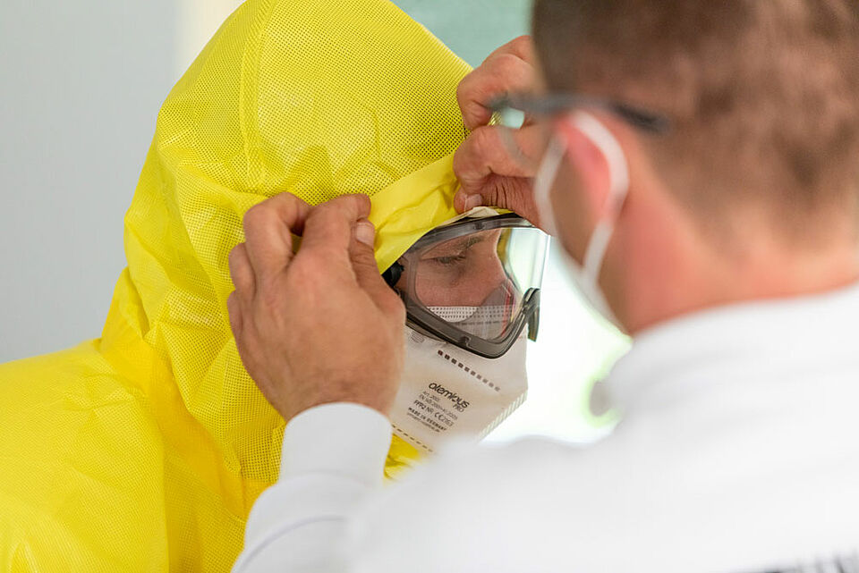 Der richtige Umgang mit der persönlichen Schutzausrüstung war wichtiger Teil des Lehrgangs. Die Schutzanzüge müssen dicht verschlossen sein, beim An- und Auskleiden darf es zu keinen Fehlern kommen. (Foto: Jonas Pröschel / BRK)