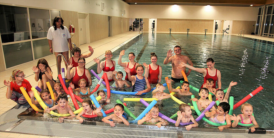 Schwimmen lernen macht Spaß: 19 Kinder haben den Herbstschwimmkurs der BRK-Wasserwacht-Ortsgruppe Ebern besucht. Mit dem Erwerb des Seepferdchens ist der Kurs jetzt zu Ende gegangen. Kursleiter James Pawlas (stehend links) und Ortsvorsitzende Michaela Hülbig (Hintergrund, 2. von links) freuen sich zusammen mit den BRK-Helferinnen und Helfern und den Kindern über den gelungenen Schwimmkurs. (Foto: Michael Will / BRK)