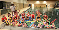 Schwimmen lernen macht Spaß: 19 Kinder haben den Herbstschwimmkurs der BRK-Wasserwacht-Ortsgruppe Ebern besucht. Mit dem Erwerb des Seepferdchens ist der Kurs jetzt zu Ende gegangen. Kursleiter James Pawlas (stehend links) und Ortsvorsitzende Michaela Hülbig (Hintergrund, 2. von links) freuen sich zusammen mit den BRK-Helferinnen und Helfern und den Kindern über den gelungenen Schwimmkurs. (Foto: Michael Will / BRK)