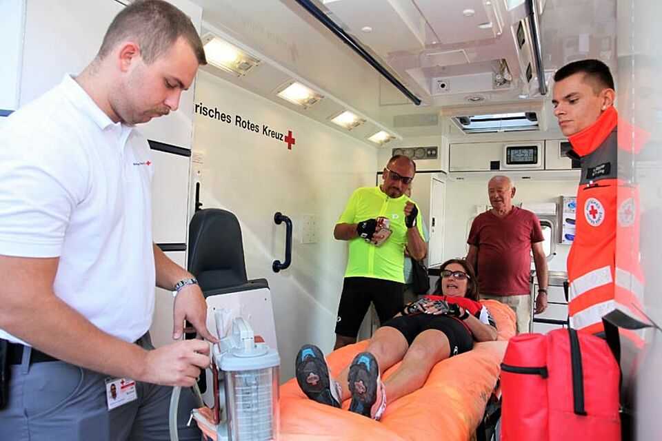 Einen Rettungswagen und seine hoch moderne medizin-technische Ausstattung konnten die Besucher beim Erste-Hilfe-Tag in Augenschein nehmen. Während Ramona Schubert unter den Augen ihres Lebensgefährte Olaf Donnerhack (2. von links) auf einer Vakuummatratze zur Probe liegt, erklären die beiden Notfallsanitäter-Auszubildenden Jan Schroll (links) und Moritz Miederhoff (rechts) wie diese funktioniert und dann sie beispielsweise bei Wirbelsäulenverletzten zum Einsatz kommt. (Foto: Michael Will / BRK)